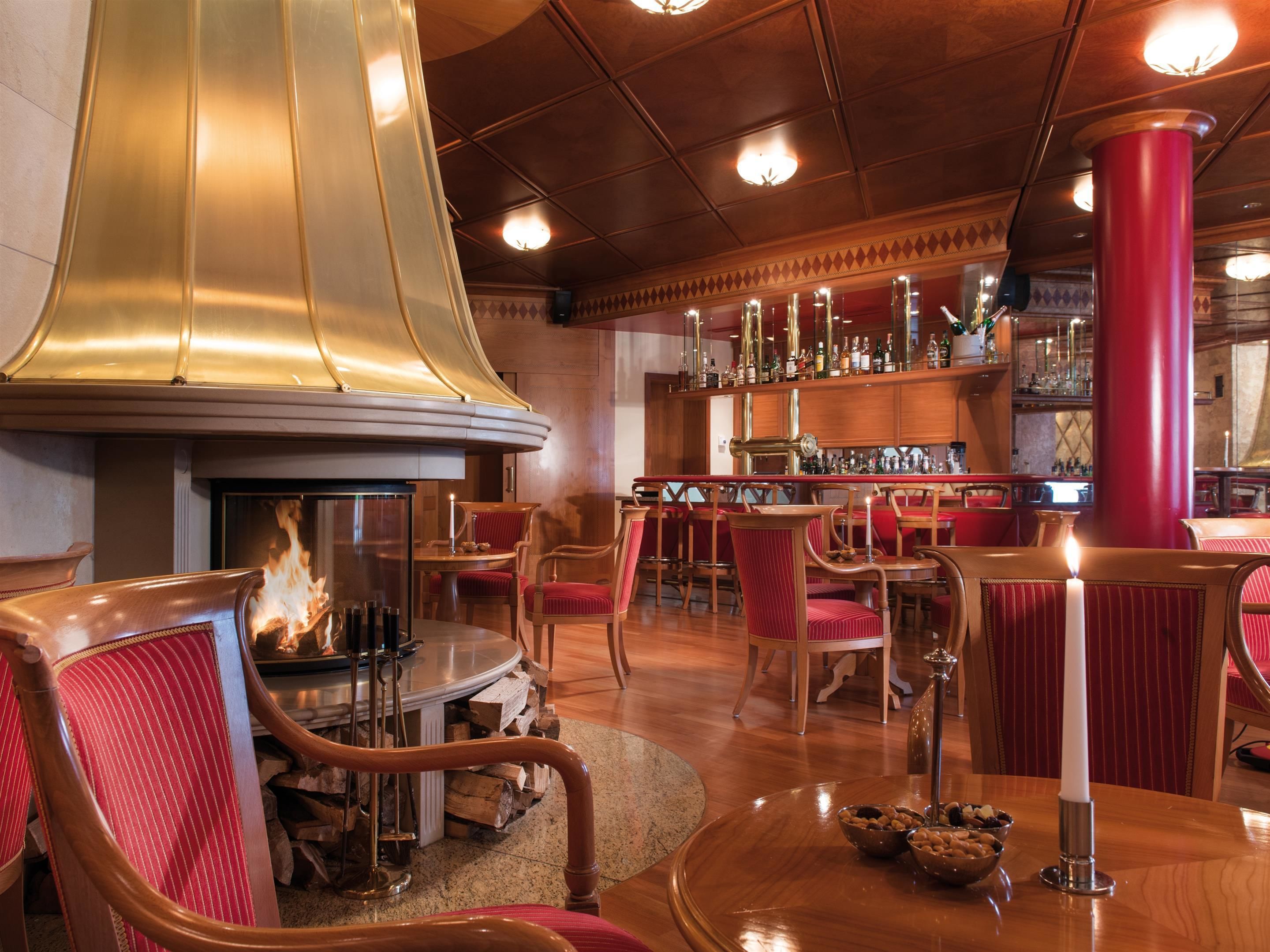 Eine gemütliche Bar mit Holzmöbeln, einem Kamin und einer Bar, die mit Flaschen gefüllt ist.