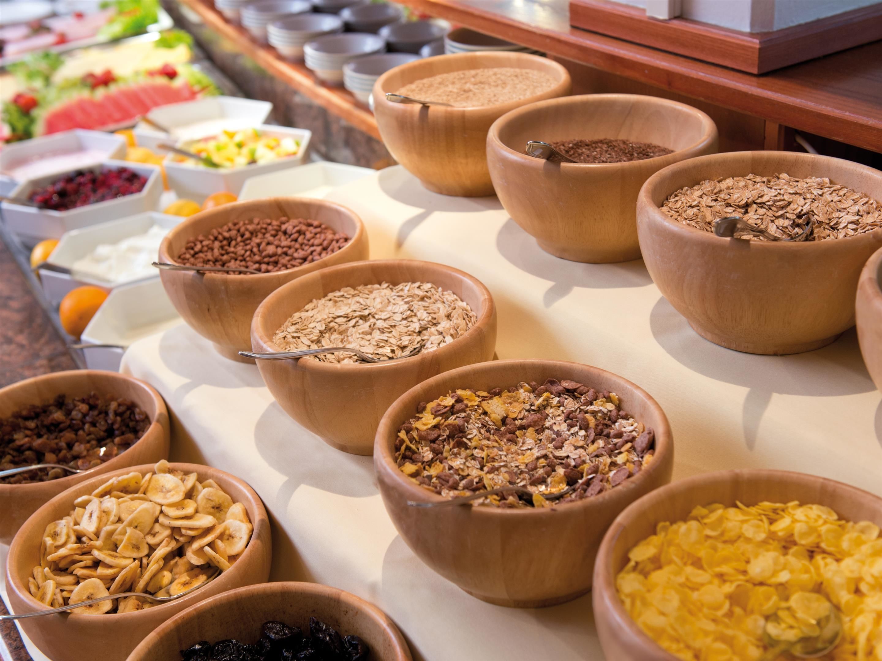 Ein Buffet mit verschiedenen Speisen in Holbschüsseln, darunter Müsli, Nüsse und Früchte.