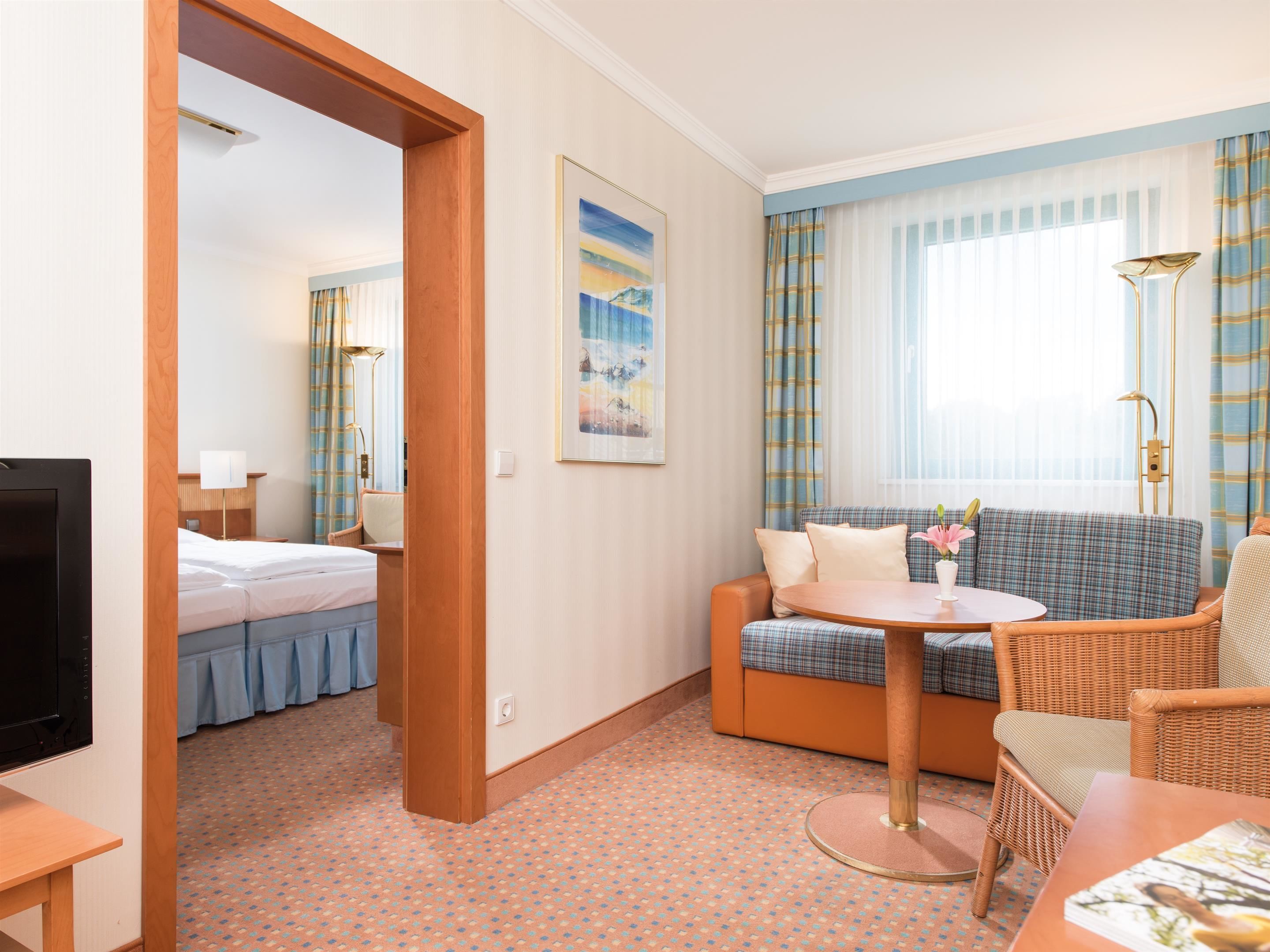 Ett hotellrum med en säng, en soffa, ett runt bord och en tv.