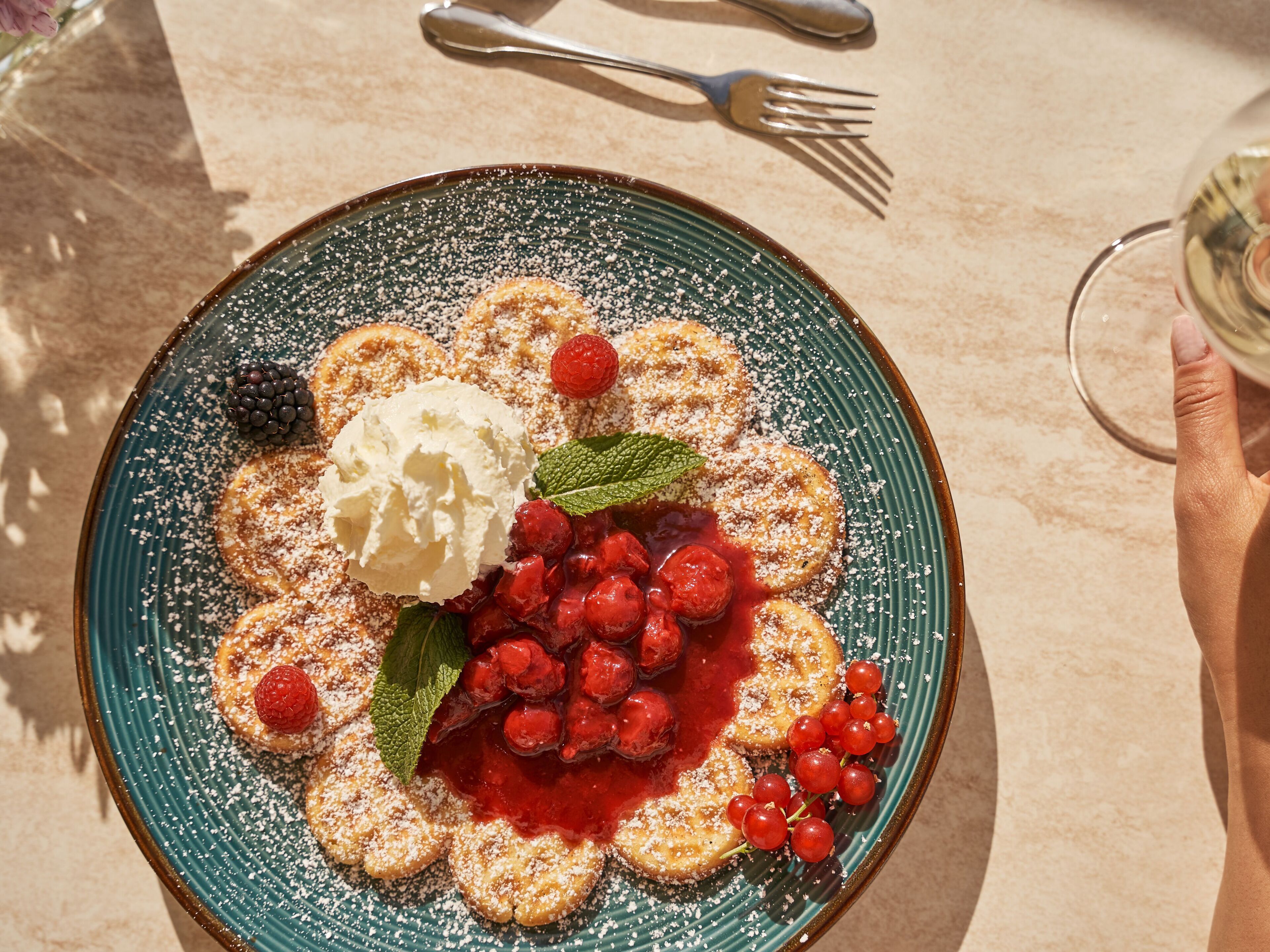 A plate of pancakes with berries and whipped cream.