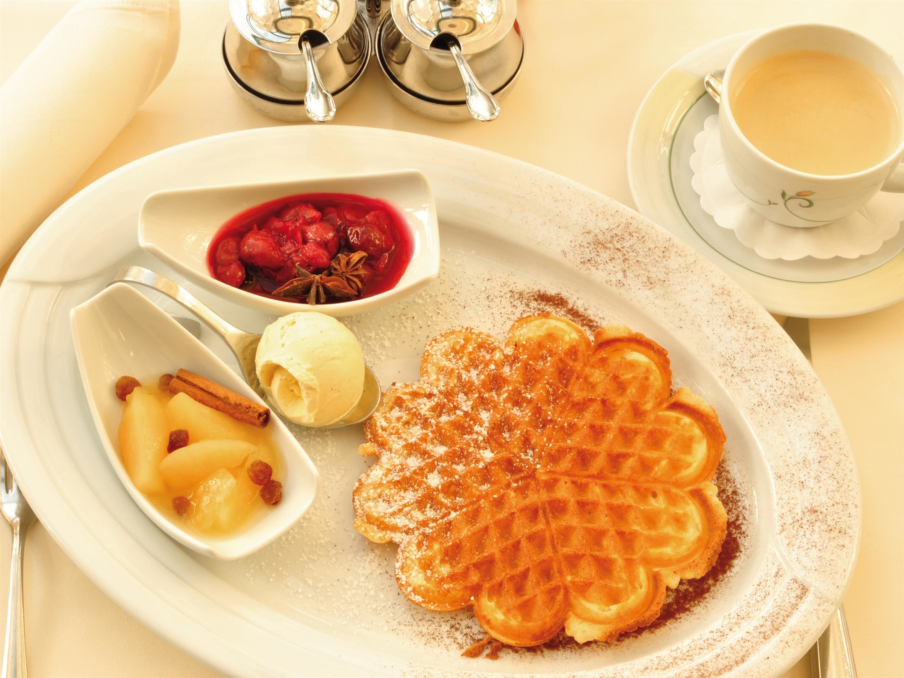 A plate with waffles, a scoop of ice cream, and a bowl of fruit.