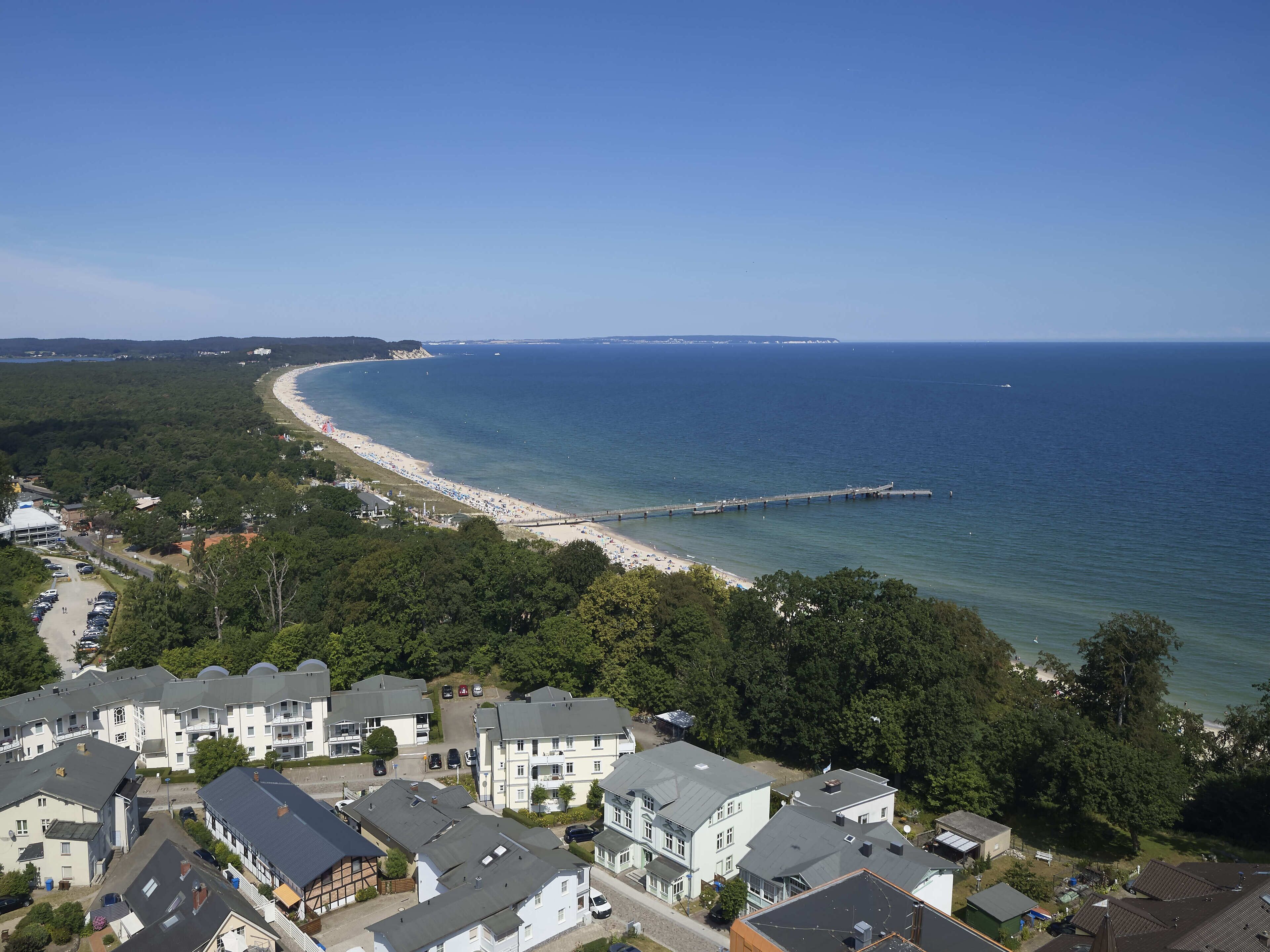 A coastal residential area with houses, a beach, and a pier.