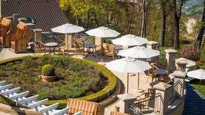 A seaside patio with outdoor seating, umbrellas, and a view of the sea.