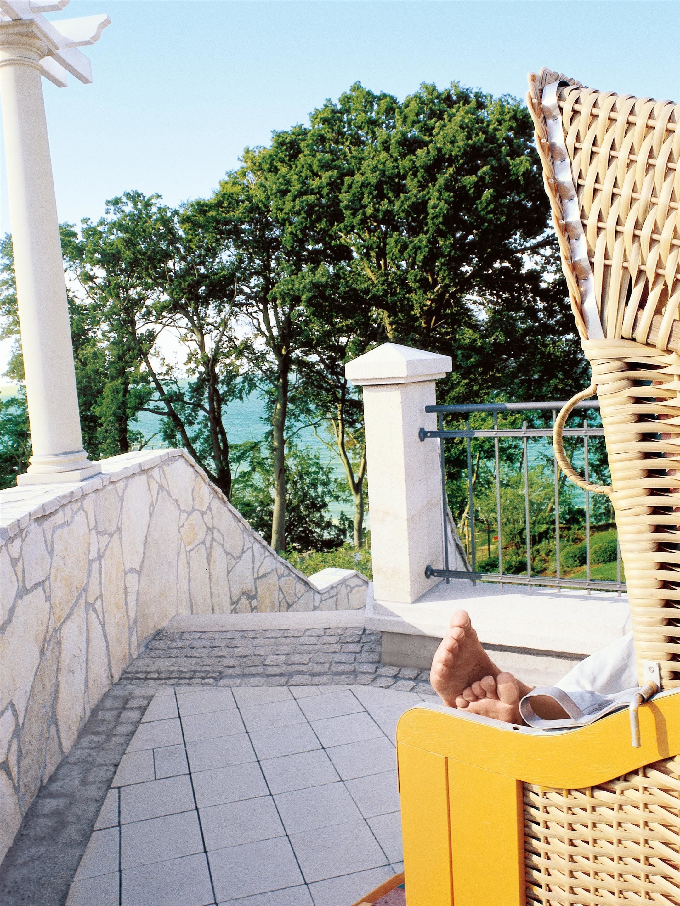 A yellow wicker chair with a stone wall and a white column in the background.