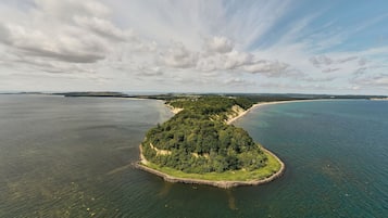 Luftaufnahme einer Küsteninsel mit üppiger Vegetation und klarem, blauem Meer.