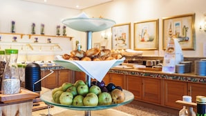 A buffet area with a glass display of fruits and pastries.
