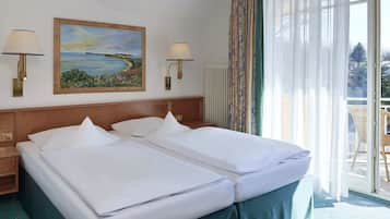 Une chambre d’hôtel avec deux lits, un tableau au mur et une vue sur l’extérieur par la fenêtre.