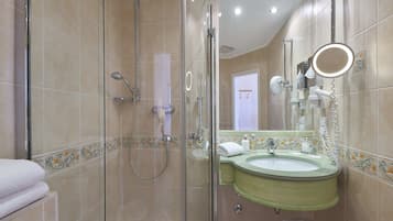 Une salle de bain dotée d’une douche à parois de verre, d’un lavabo avec un receveur vert et d’un miroir avec un éclairage circulaire.