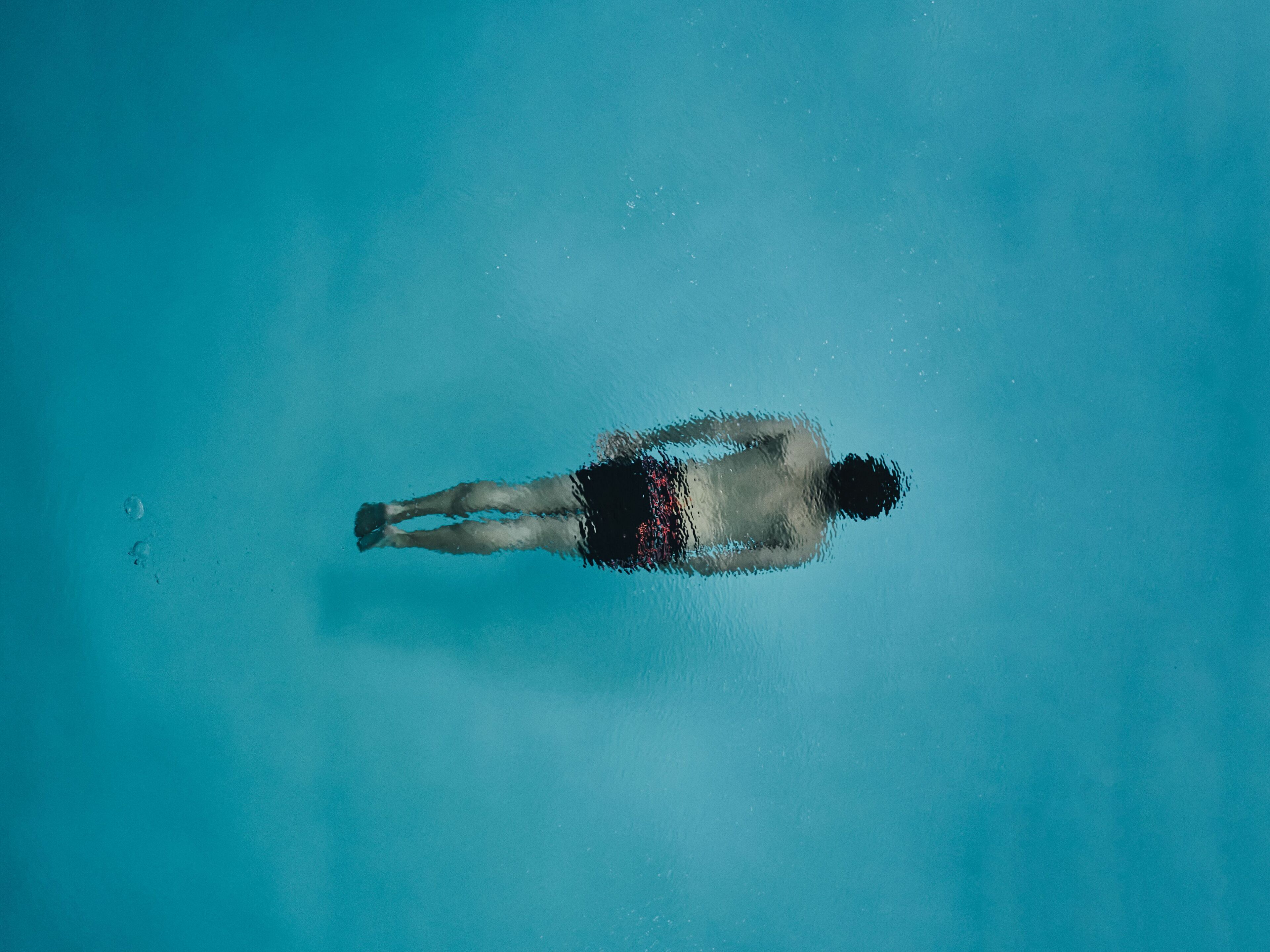 Eine Person schwimmt in einem klaren, blauen Pool.
