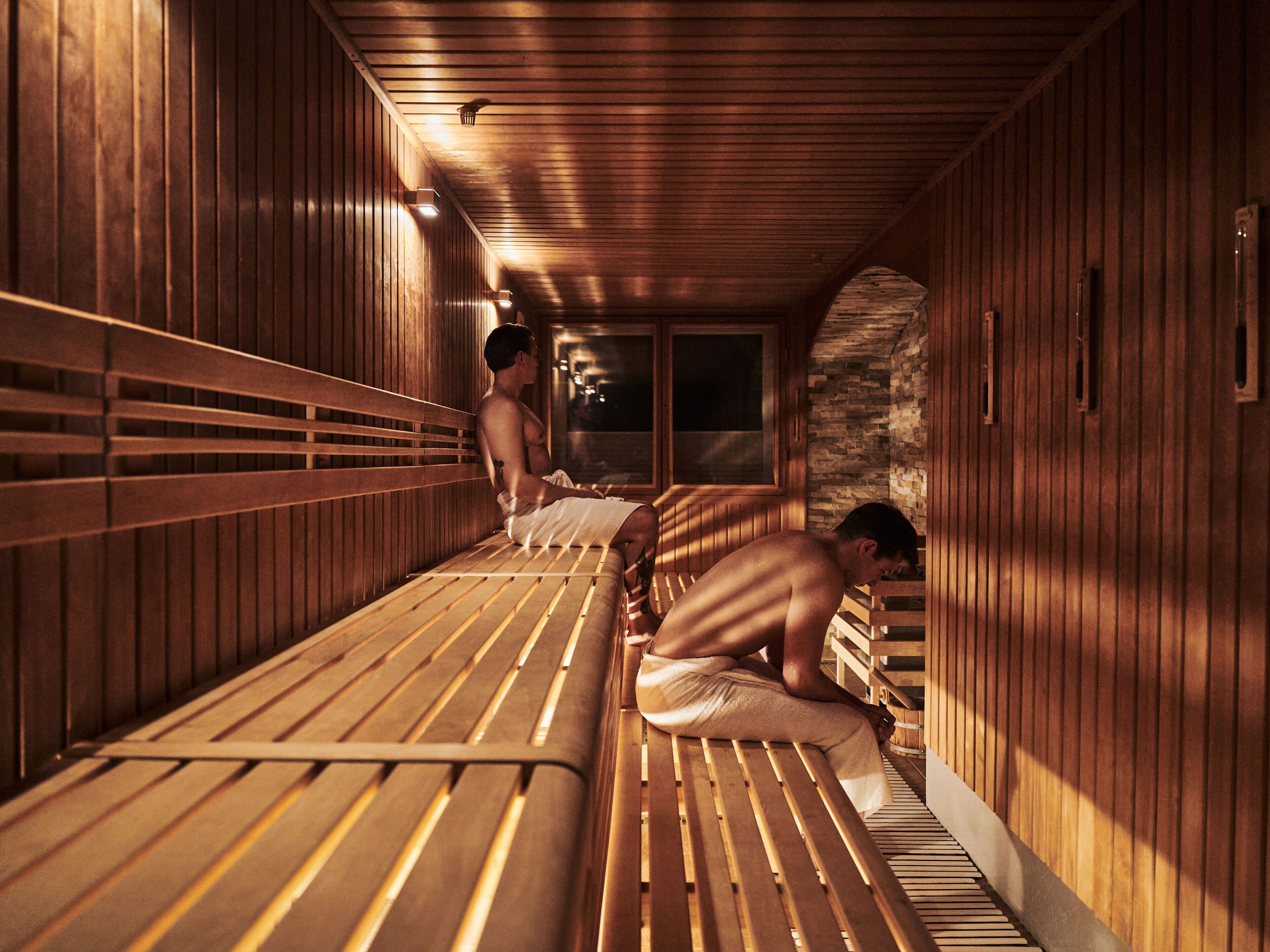 Eine Sauna mit Holzbänken und einer Steinwand.