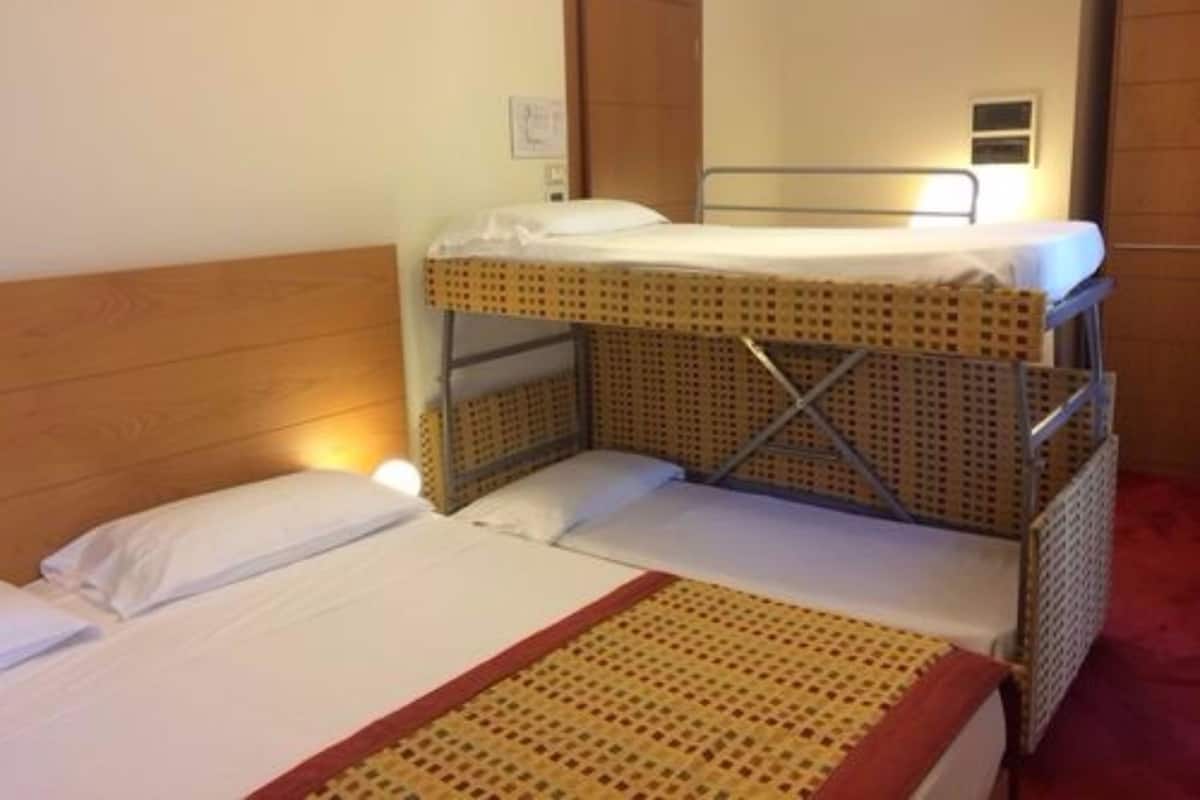 A bunk bed room with a wooden headboard, a small bedside table, and a wall-mounted light.