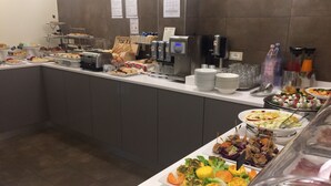 Un bufé con diferentes opciones de comida, como ensaladas, sándwiches y un dispensador de yogur.