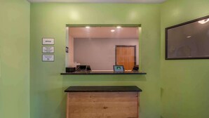 Zona de recepción con mostrador de entrada, un escritorio de madera y un cuadro enmarcado en la pared.