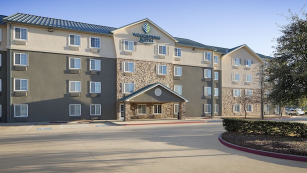 Un hotel de varios pisos con fachada de piedra y un letrero que dice "Woodspring Suites".