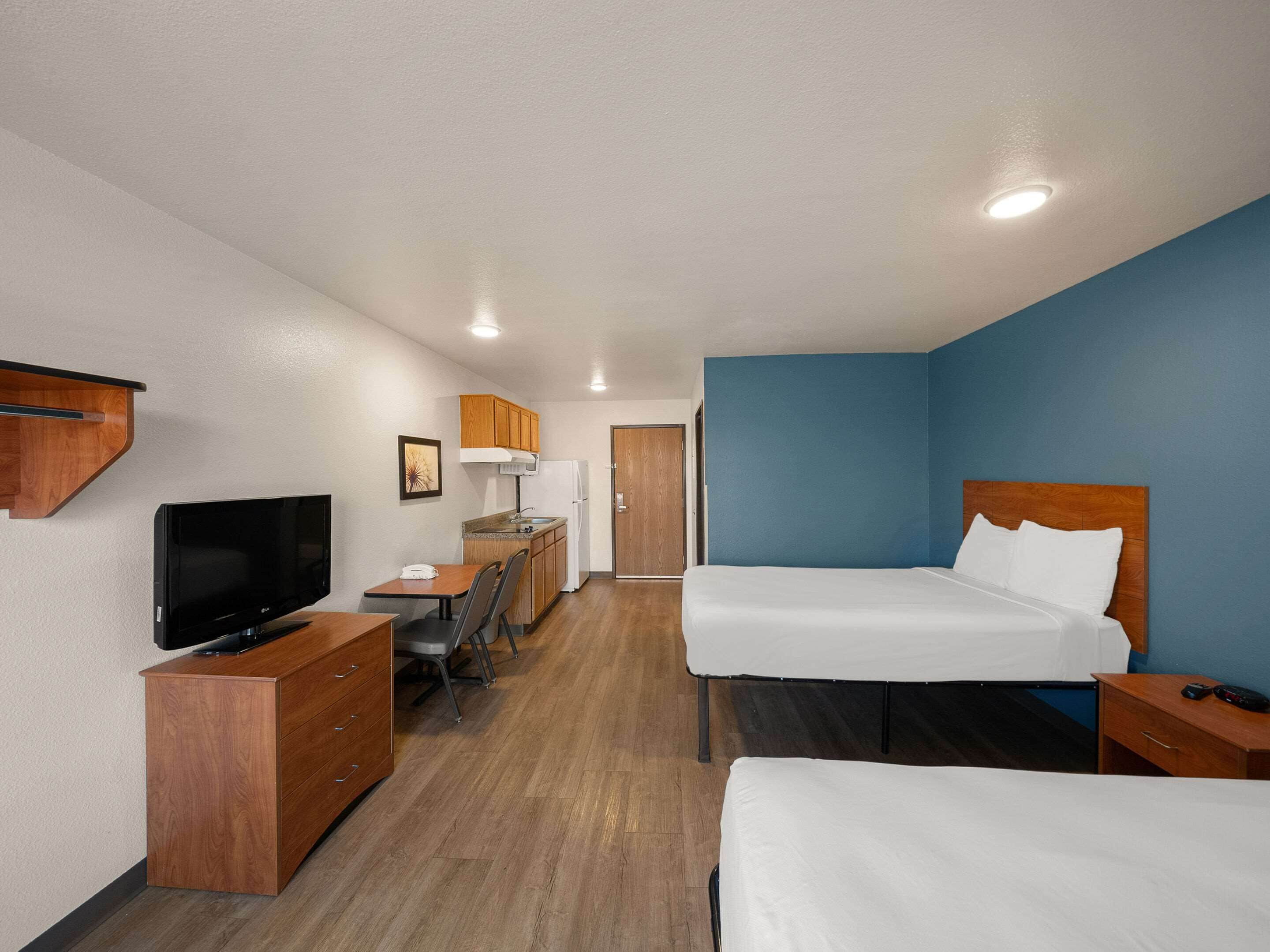 Een hotelkamer met twee bedden, een bureau met stoel, een televisie en een kledingkast.