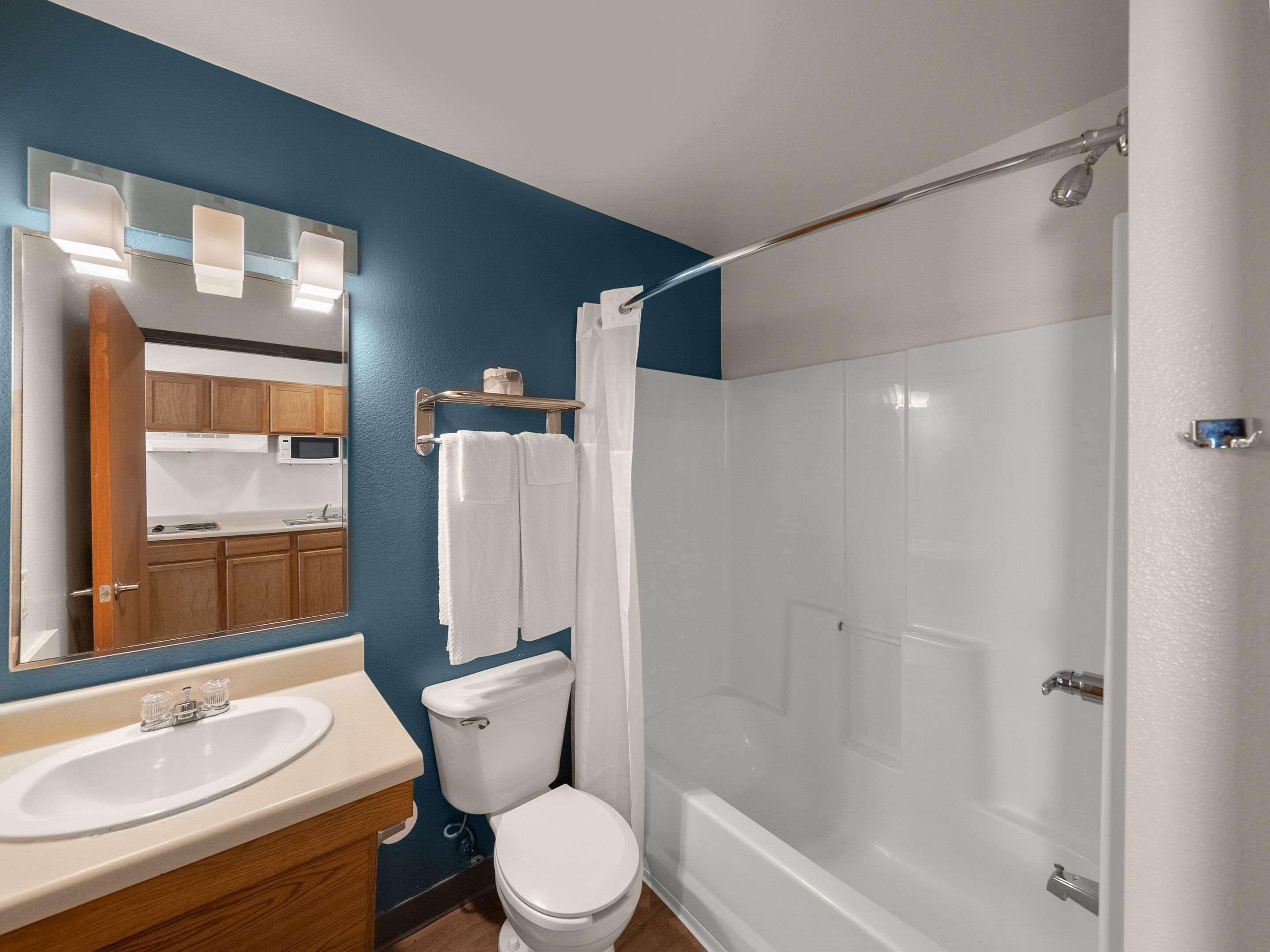 A bathroom with a white sink, toilet, and bathtub. There is a mirror above the sink and a shower curtain over the bathtub.