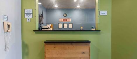 Un área de recepción con un escritorio de madera, mostrador de registro, un teléfono y certificados enmarcados en la pared.