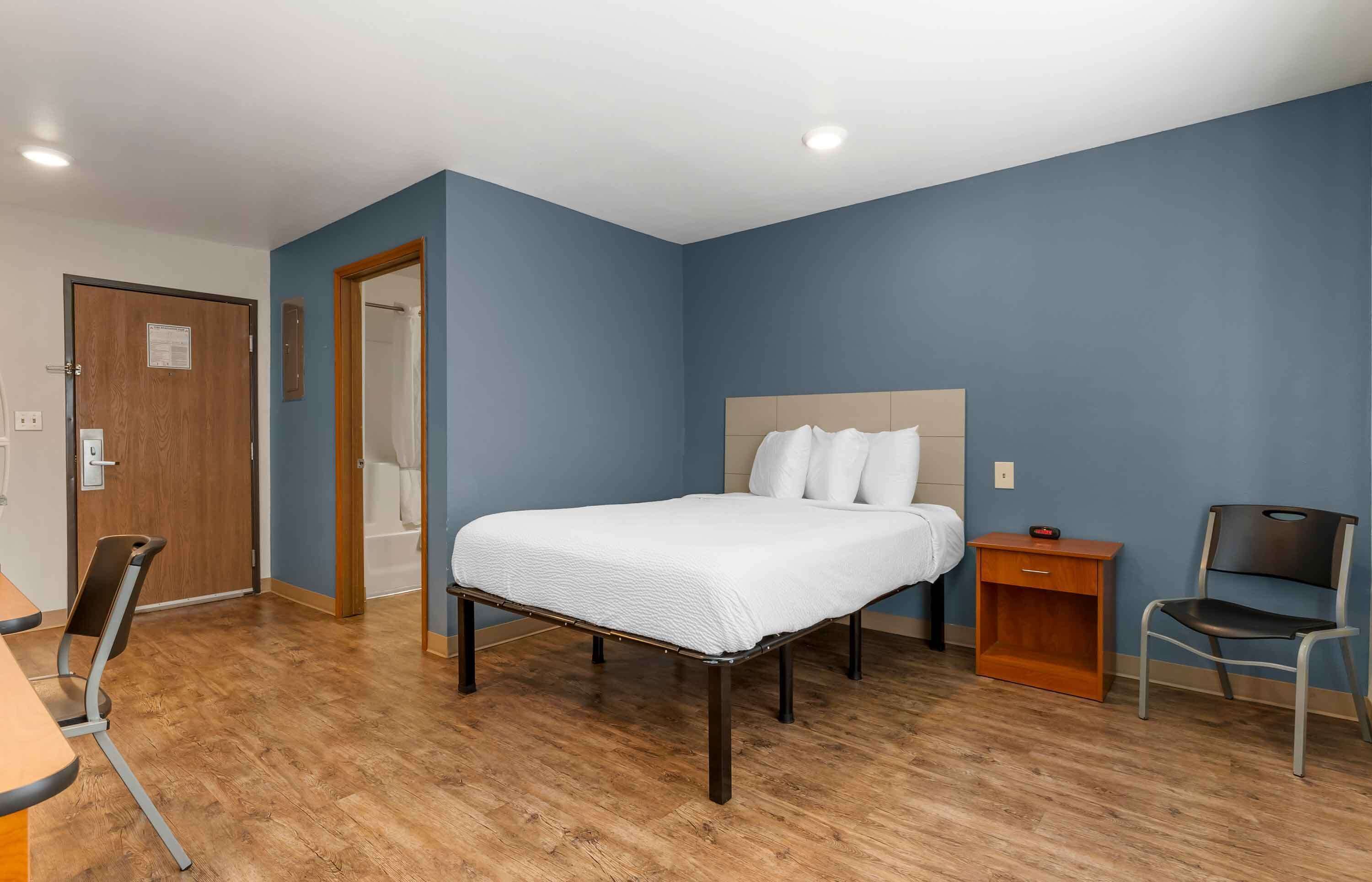 Une chambre à coucher avec un lit, une chaise, une table de chevet et une table en bois.