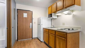 Una cocina compacta con armarios de madera, un refrigerador blanco, un microondas y una estufa.