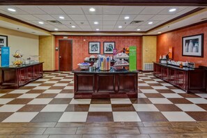 A hotel lobby with a checkered floor, a buffet counter, and a reception desk. - Hampton Inn Corsicana (Corsicana)