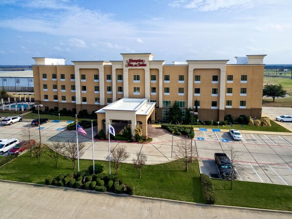 A Hampton Inn & Suites hotel with a parking lot, flagpoles, and a clear sky. - Hampton Inn Corsicana (Corsicana)