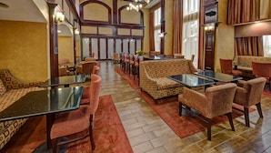 A hotel lobby with a mix of seating options including sofas and chairs, a central dining table, and a patterned carpet. - Hampton Inn Corsicana (Corsicana)