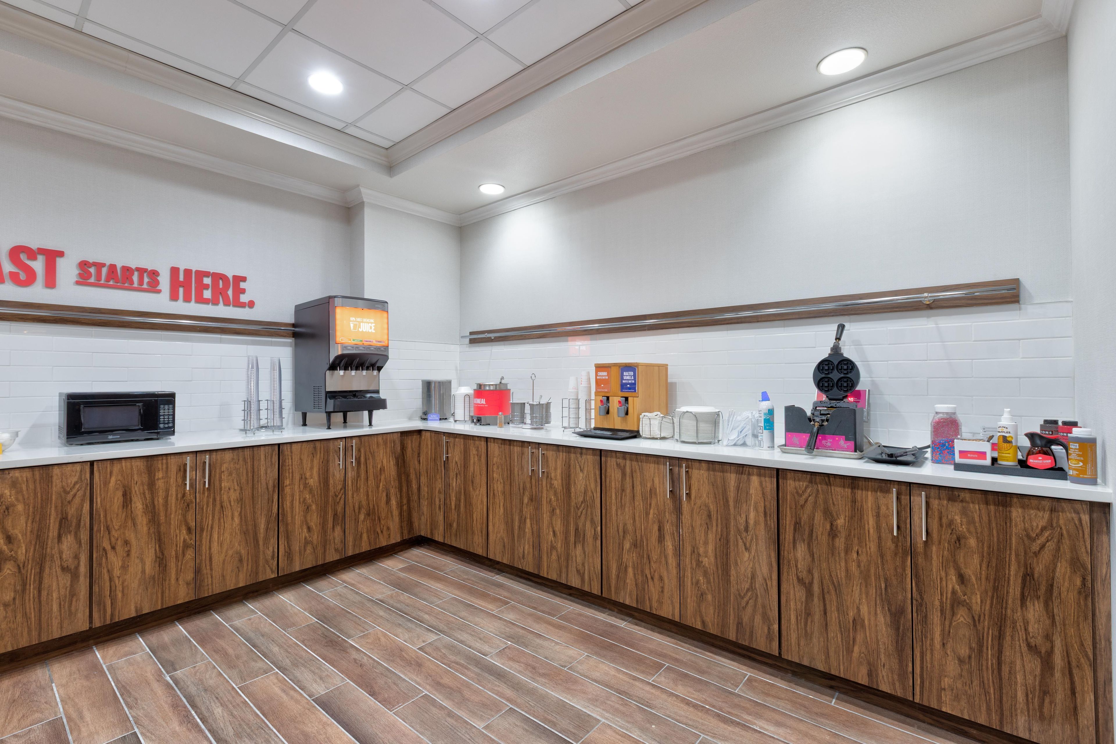A modern kitchen with a microwave, coffee machine, and a sign that reads 'STARTS HERE.'
