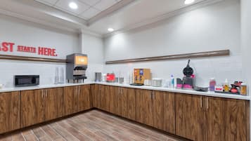 A modern kitchen with a microwave, coffee machine, and a sign that reads 'STARTS HERE.'