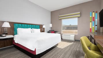 Habitación de hotel con una cama grande, dos mesitas de noche, un escritorio, una silla, un ventanal con vistas y un televisor de pantalla plana.
