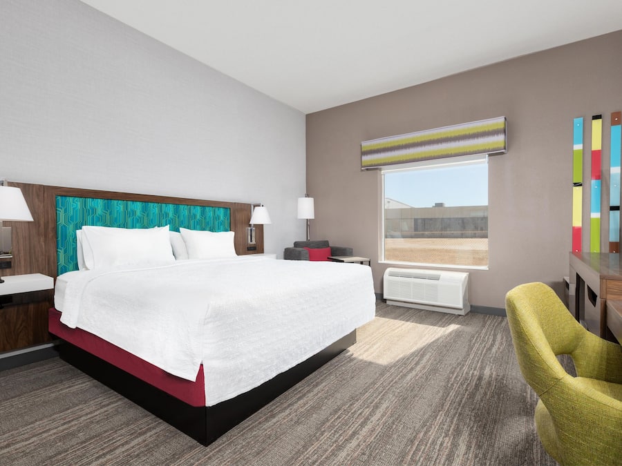 Quarto de hotel com uma cama grande, duas mesas de cabeceira, uma escrivaninha, uma cadeira, uma janela com vista e uma TV de tela plana.