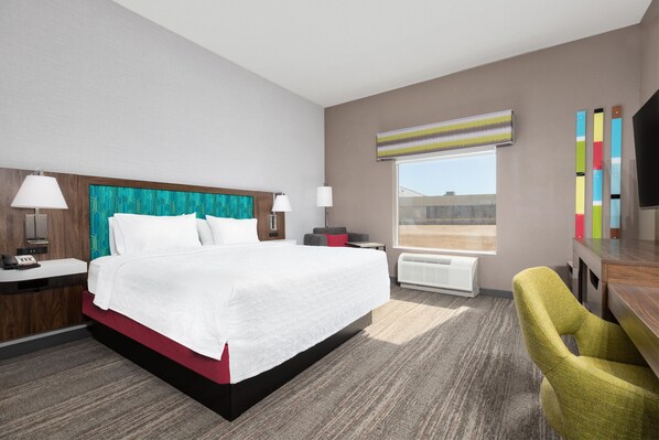 Habitación de hotel con una cama grande, dos mesitas de noche, un escritorio, una silla, un ventanal con vistas y un televisor de pantalla plana.
