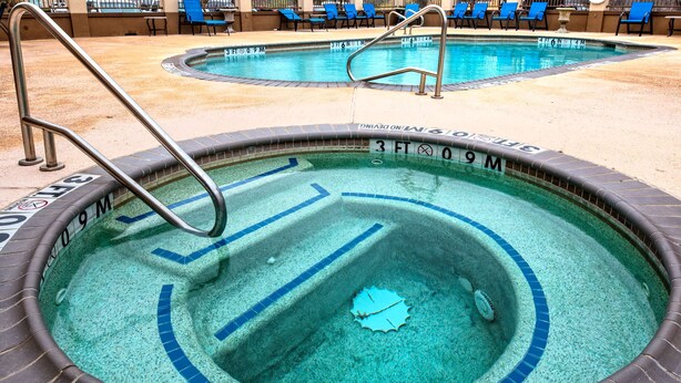 A hot tub with a tiled edge and a metal ladder. - Hampton Inn Corsicana (Corsicana)