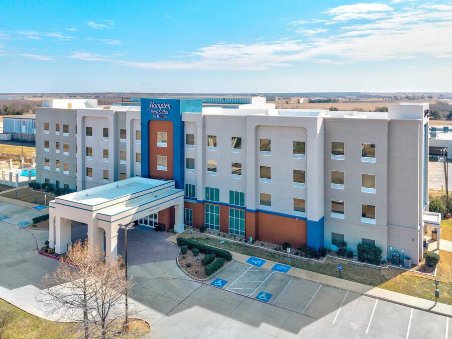 A multi-story hotel with a prominent entrance and a parking lot with handicapped accessible spaces.