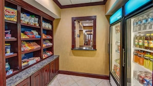 A hotel pantry with shelves stocked with snacks and a refrigerator filled with beverages. - Hampton Inn Corsicana (Corsicana)