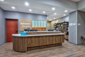 A reception desk with a 'Welcome to Hampton' sign, a 'Hilton Honors' sign, and a 'Treats Shop' sign. - Hampton Inn Corsicana (Corsicana)