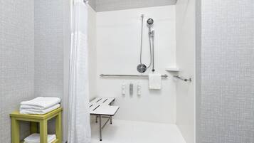 Un baño moderno con ducha, toallero y una mesita con toallas.