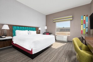 A hotel room with a large bed, two bedside tables, a desk, a chair, a window with a view, and a flat-screen TV. - Hampton Inn Corsicana (Corsicana)