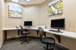 A modern office space with two desks, each equipped with a computer, keyboard, and mouse. There are two office chairs, one on each desk. The walls are adorned with two landscape paintings. - Hampton Inn Corsicana (Corsicana)