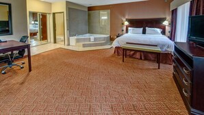 A hotel room with a bed, a desk, a chair, a TV, a dresser, a bathroom with a bathtub, and a shower. - Hampton Inn Corsicana (Corsicana)
