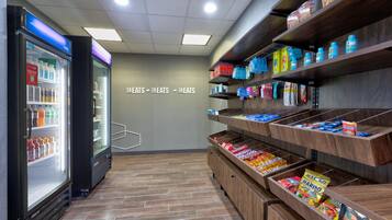 A self-service snack area with refrigerated drinks and a variety of packaged snacks on shelves.