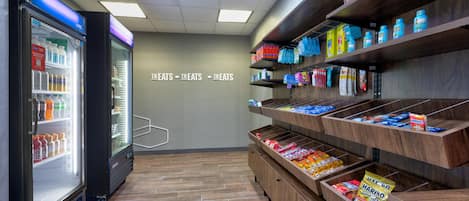 A self-service snack area with refrigerated drinks and a variety of packaged snacks on shelves.