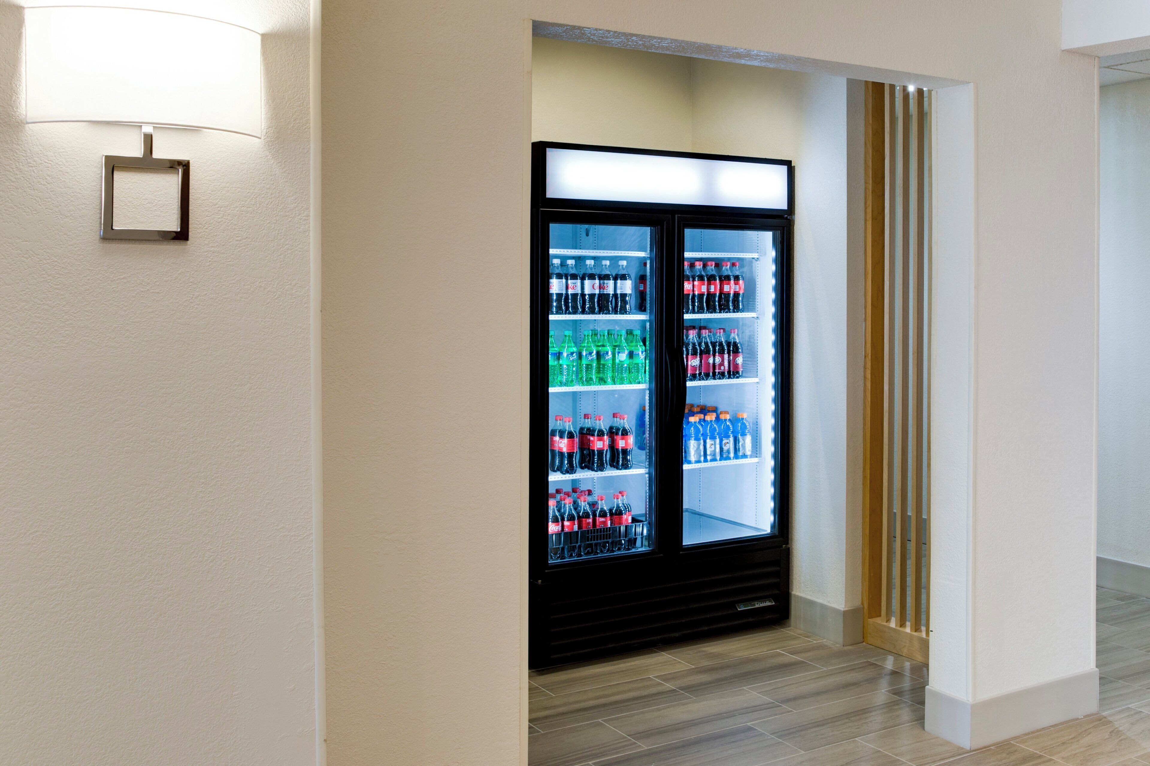 A hotel corridor with a vending machine stocked with beverages.