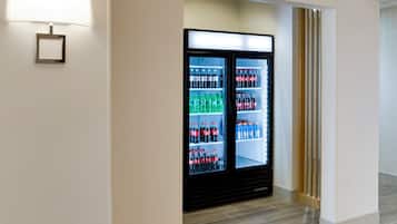 A hotel corridor with a vending machine stocked with beverages.