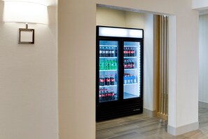 A hotel corridor with a vending machine stocked with beverages.