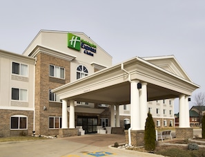 A Holiday Inn Express Suites building with a covered entrance, brick facade, and multiple windows.