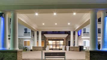 A covered outdoor area with columns, a bench, and a building entrance.