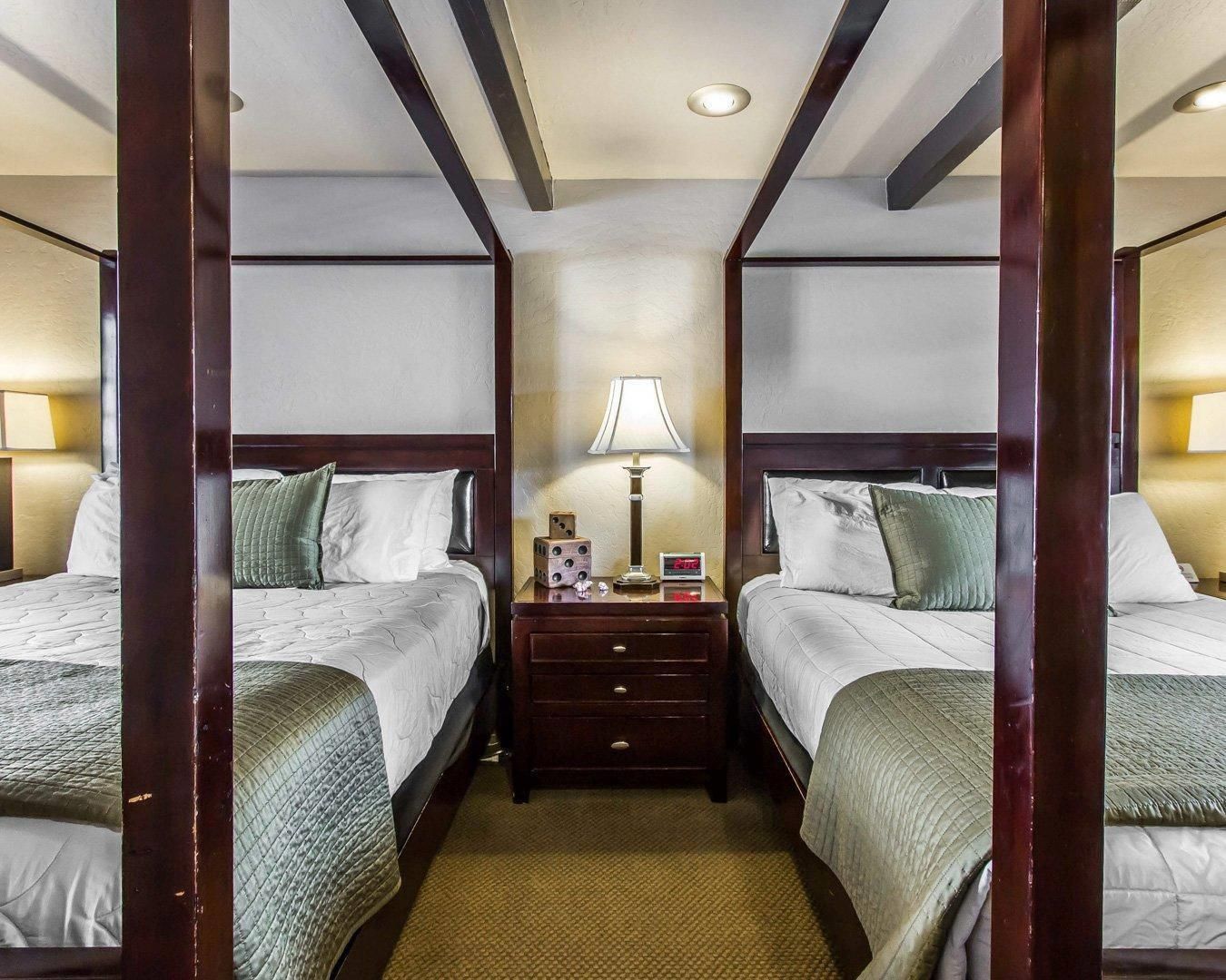 Une chambre d’hôtel avec deux lits, une table de chevet avec une lampe et une horloge murale.