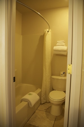 A small, compact bathroom with a bathtub, toilet, and shower curtain. - Rodeway Inn & Suites Williams Downtowner - Rte 66 (Williams)