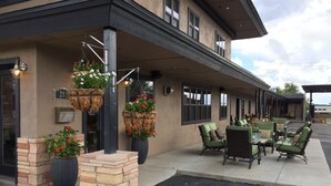 A building with outdoor seating, hanging flower baskets, and a brick planter. - Rodeway Inn & Suites Williams Downtowner - Rte 66 (Williams)