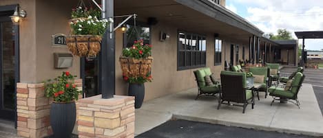A building with outdoor seating, hanging flower baskets, and a brick planter.